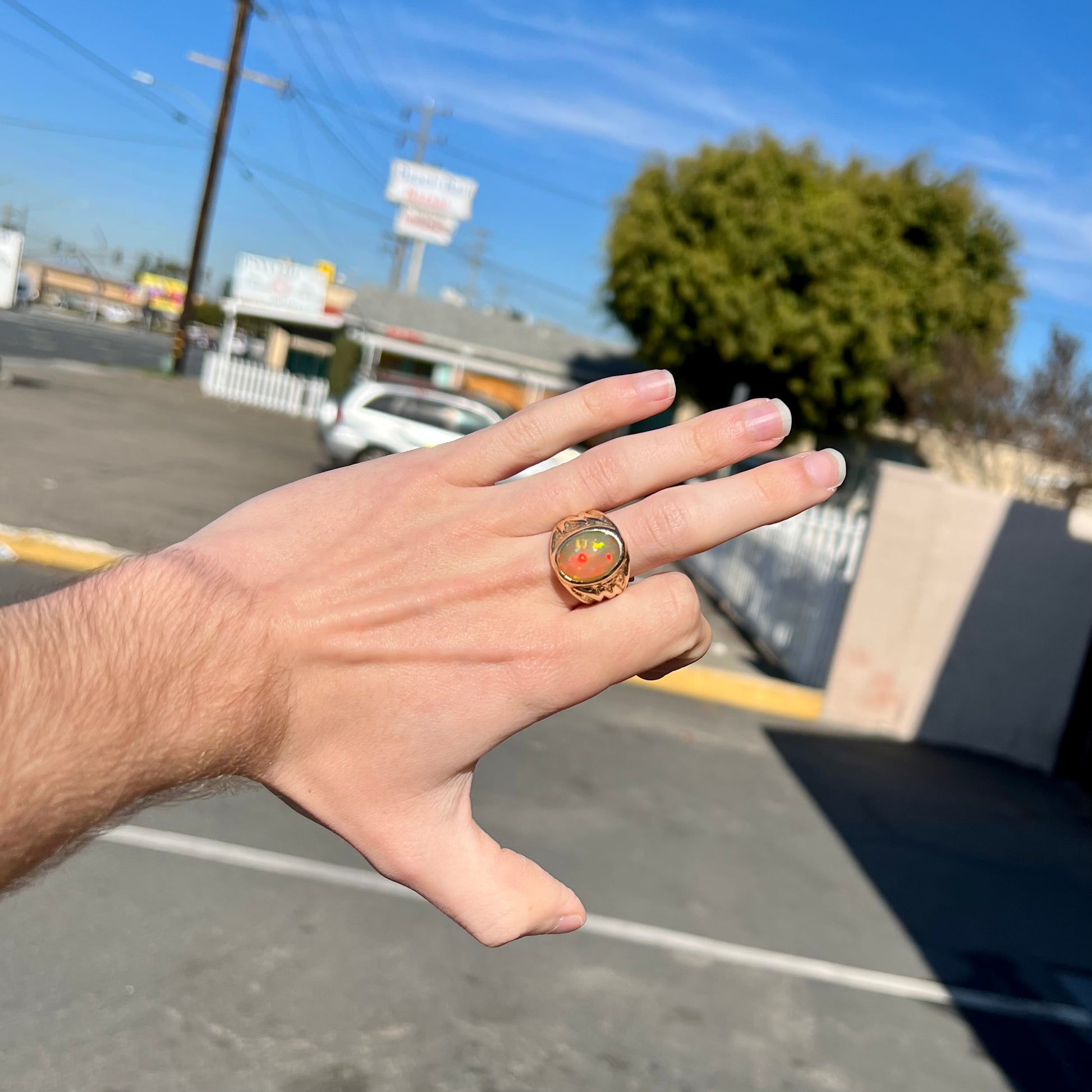 A solid yellow gold solitaire men's fire opal ring.  The stone is an orange oval cabochon cut.