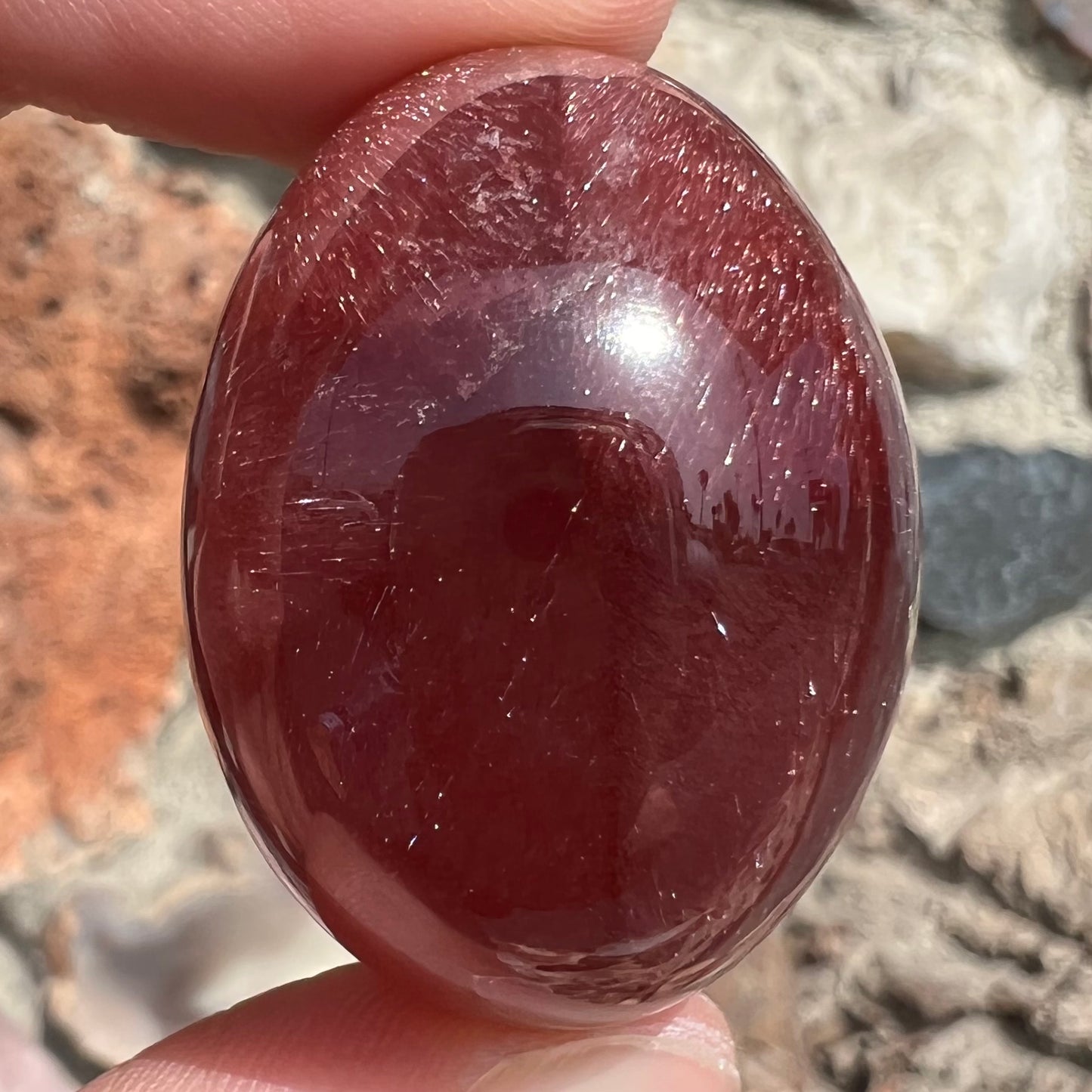 A large, oval cabochon cut strawberry quartz. The stone has a trapiche star-like pattern.