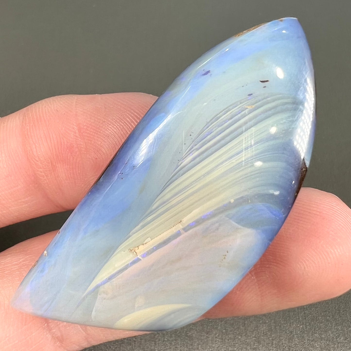 A loose, polished blue boulder opal stone from Queensland, Australia.