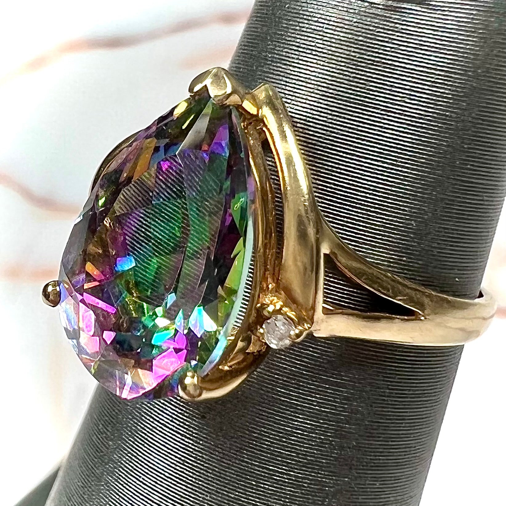 Pear shape green and pink mystic topaz set in a yellow gold ring with a single round diamond.