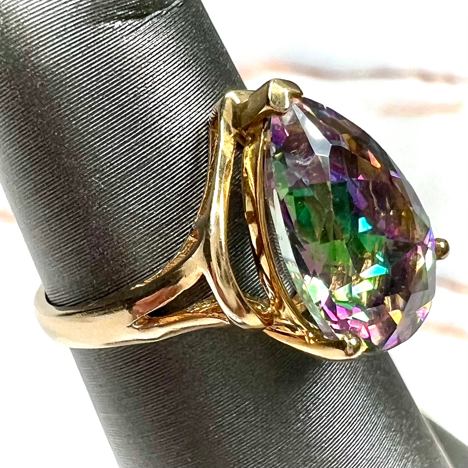 Pear shape green and pink mystic topaz set in a yellow gold ring with a single round diamond.