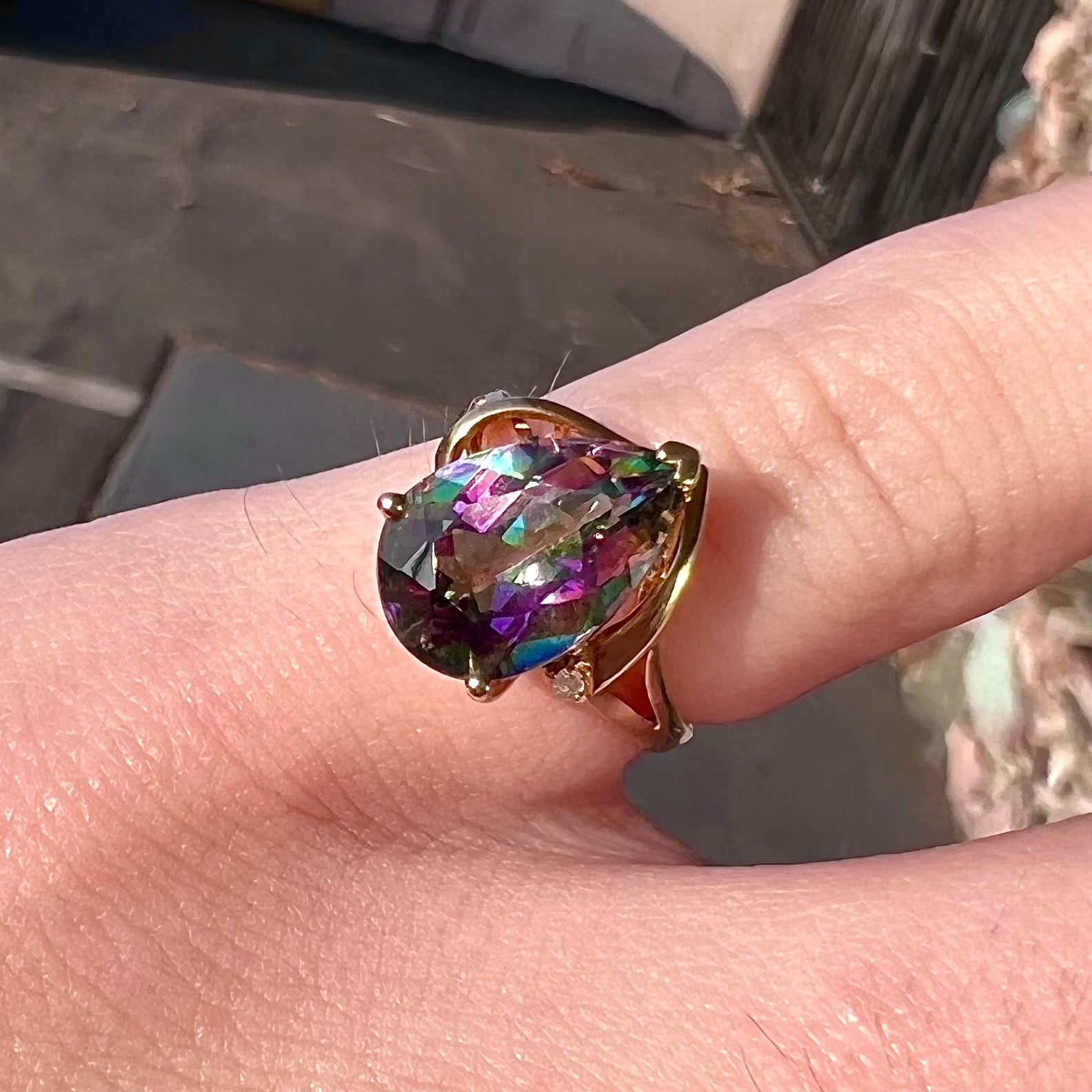 Pear shape green and pink mystic topaz set in a yellow gold ring with a single round diamond.