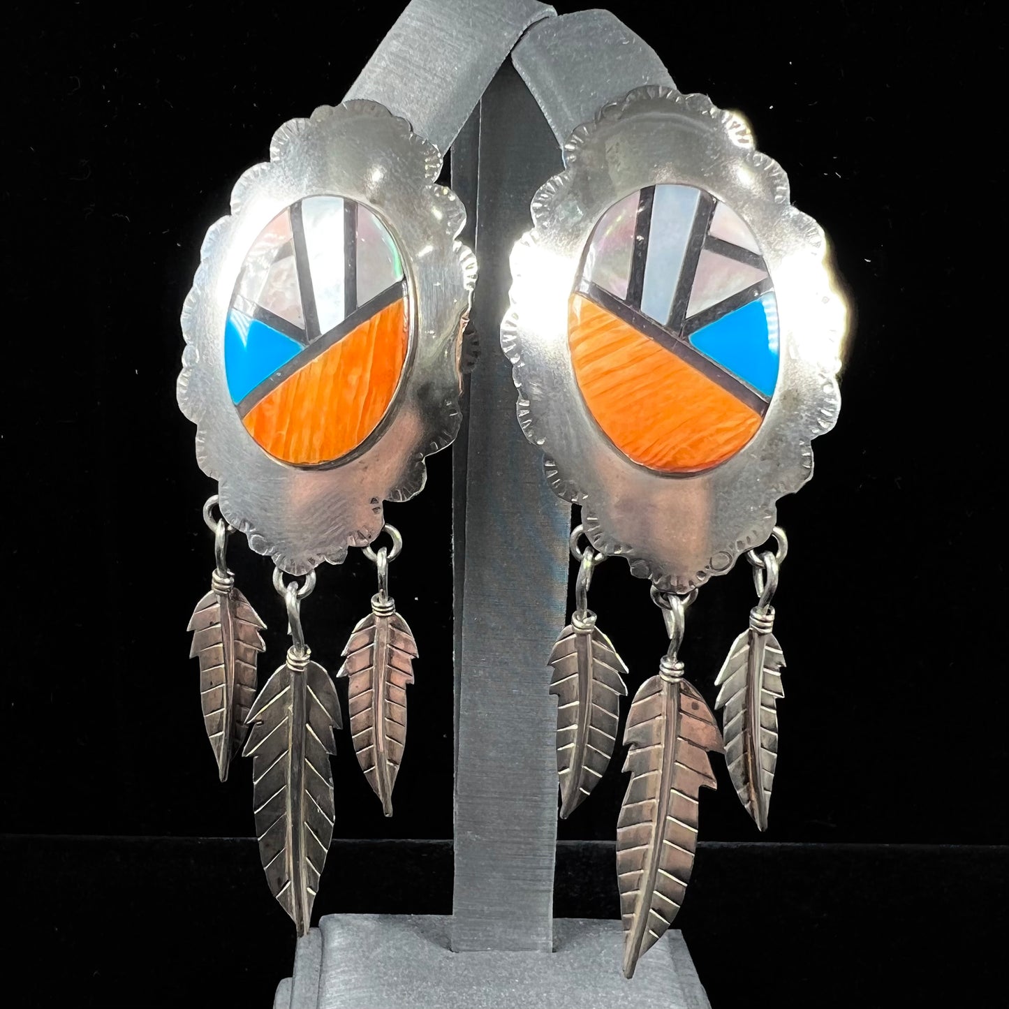 A pair of Native American style feather dangle earrings inlaid with mother of pearl shell and turquoise.