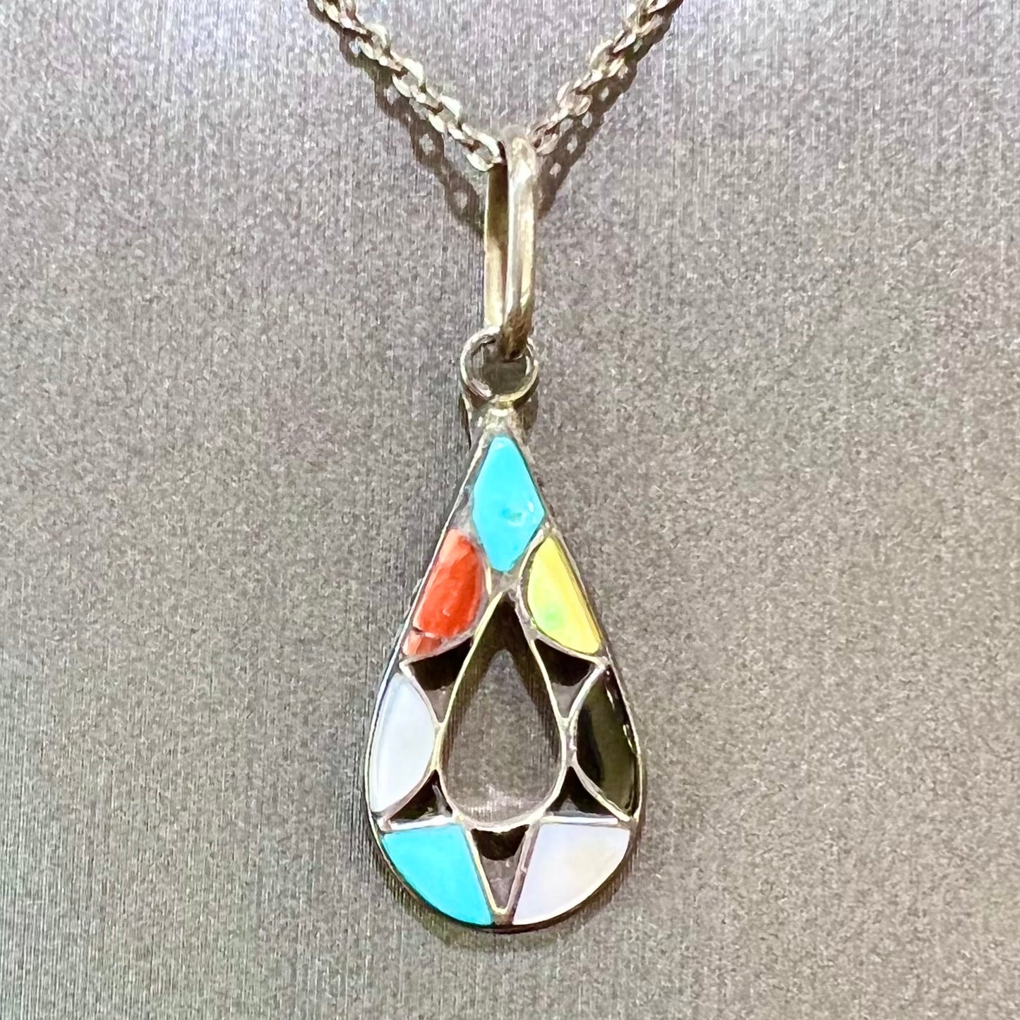 Photo of Zuni Indian pendant with stone inlay of coral, onyx, turquoise, jasper, and mother of pearl.