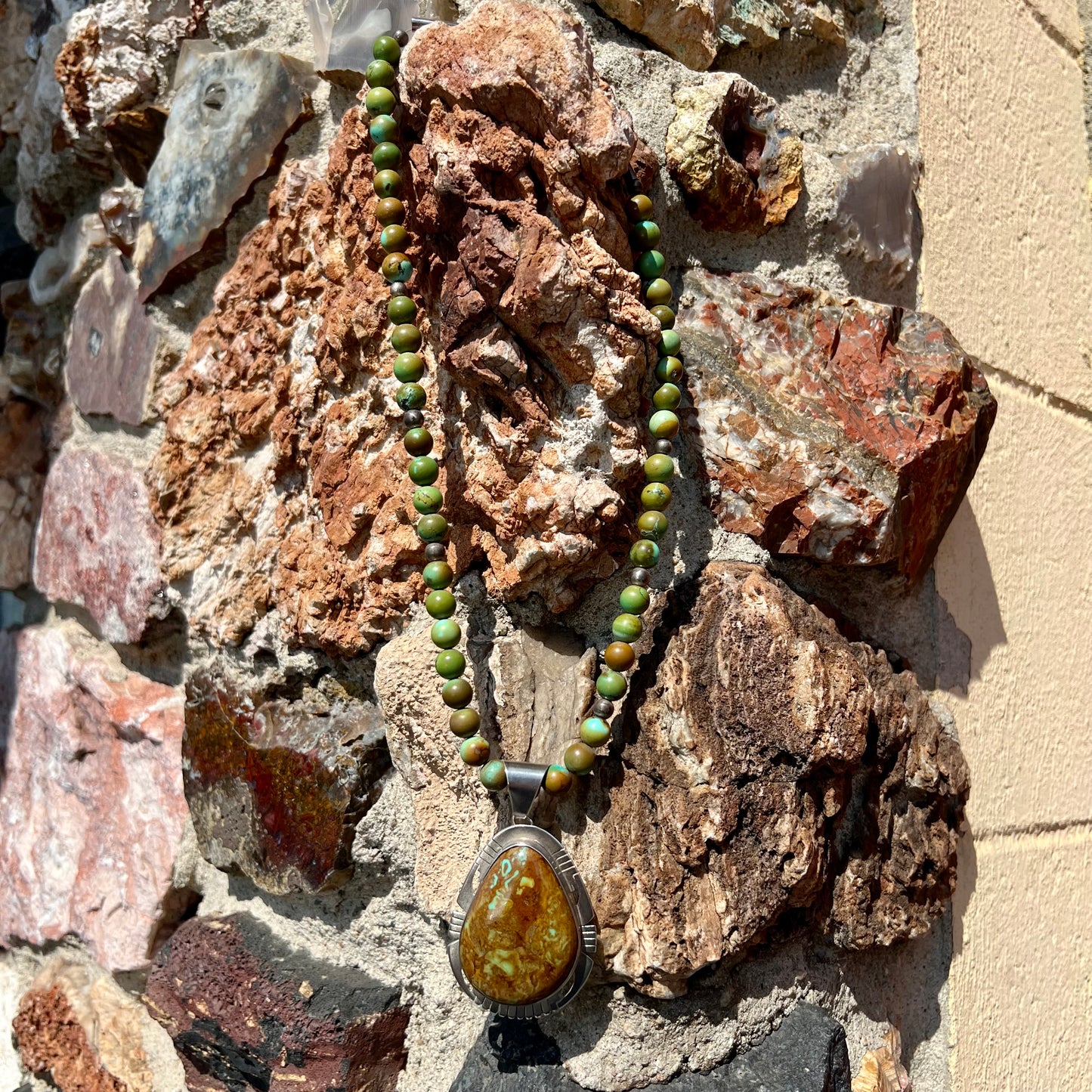A handmade, likely Navajo silver pendant set with Kingman turquoise on a green Kingman turquoise beaded necklace.
