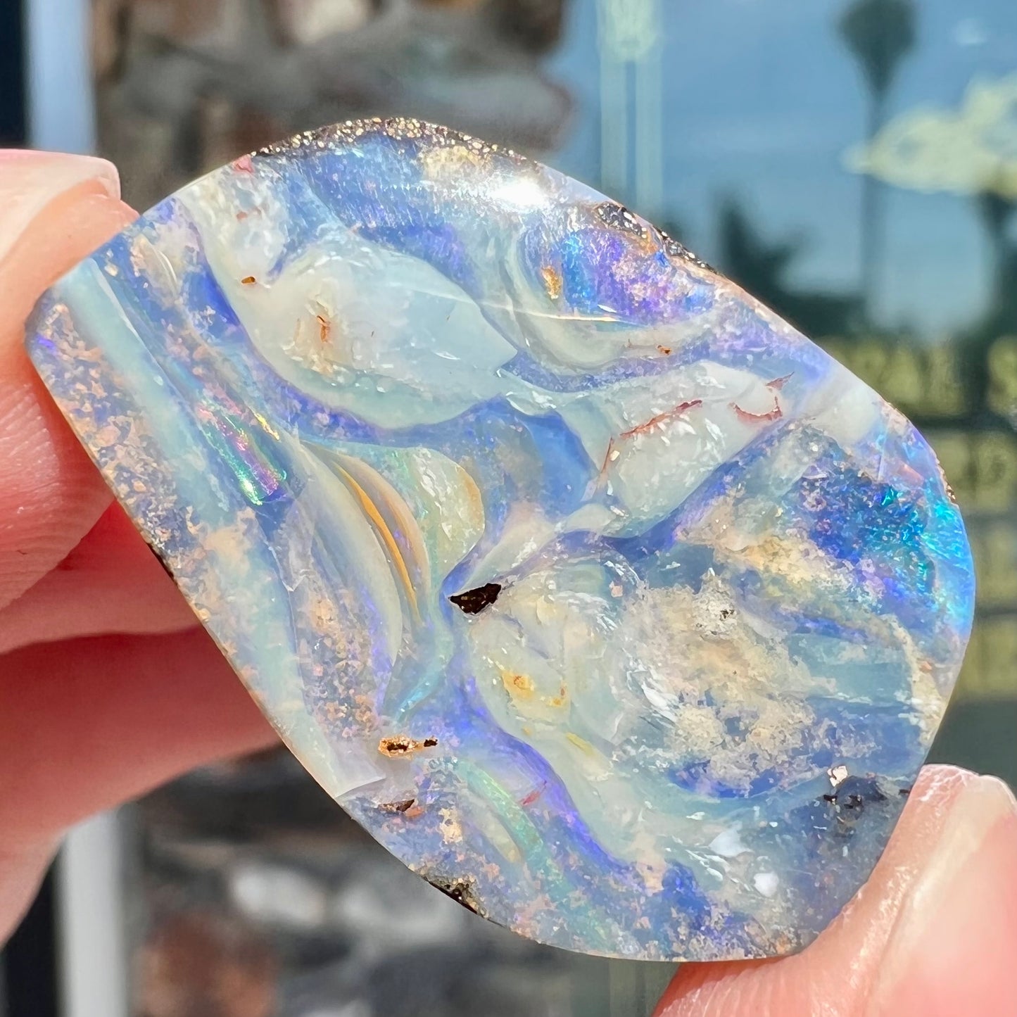A loose, polished, freeform cut boulder opal stone from Queensland, Australia.