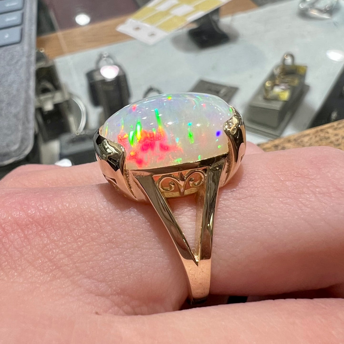 A ladies' yellow gold split shank ring half-bezel set with a barrel cabochon cut natural Ethiopian fire opal stone.
