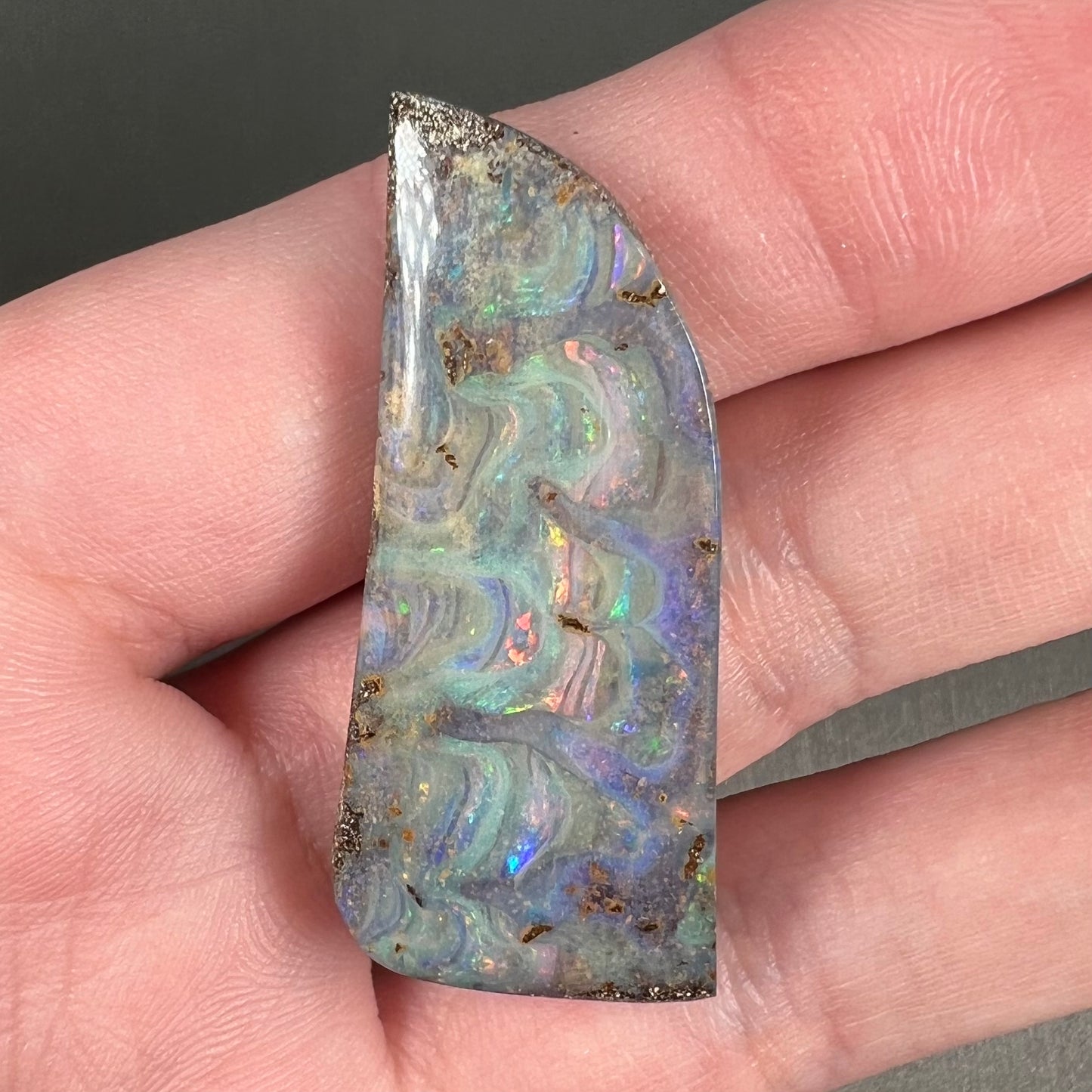 A loose, freeform cut, natural boulder opal stone from Quilpie, Australia.