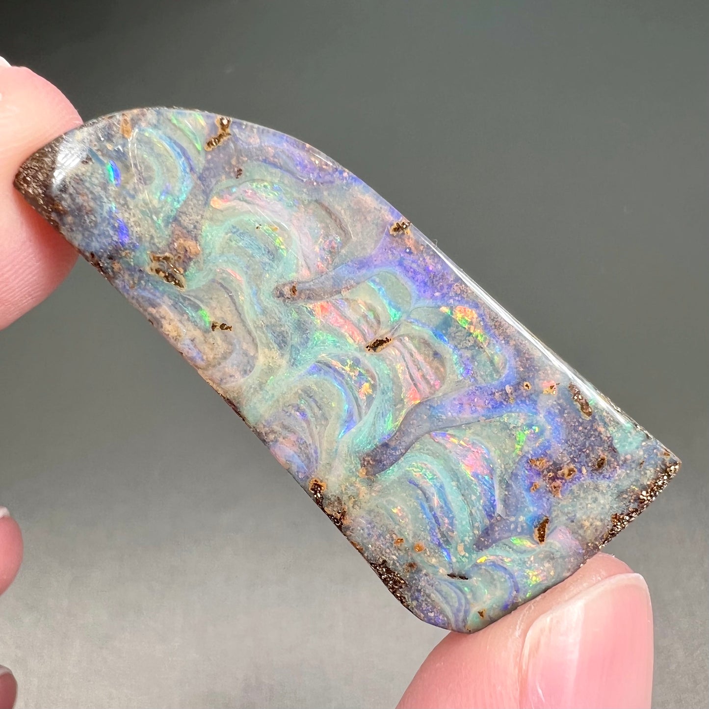 A loose, freeform cut, natural boulder opal stone from Quilpie, Australia.