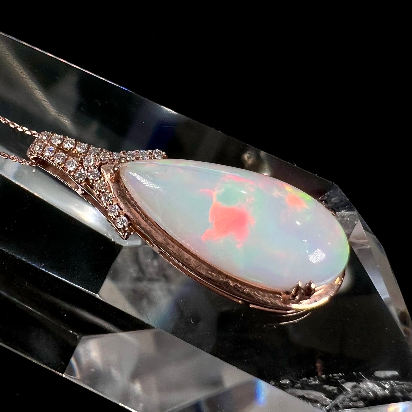 A rose gold, teardrop shaped fire opal and diamond necklace on a cable chain.