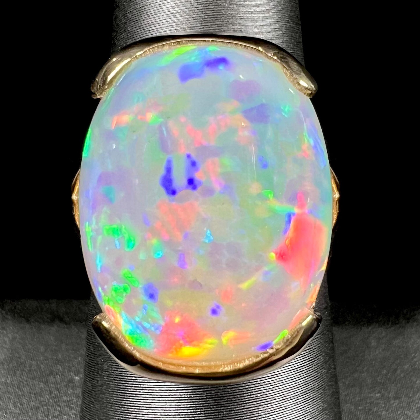 A ladies' yellow gold split shank ring half-bezel set with a barrel cabochon cut natural Ethiopian fire opal stone.