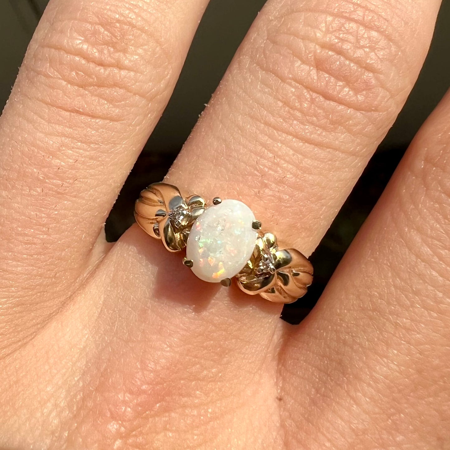 A ladies' yellow gold white crystal opal and diamond ring. The opal is prong set.