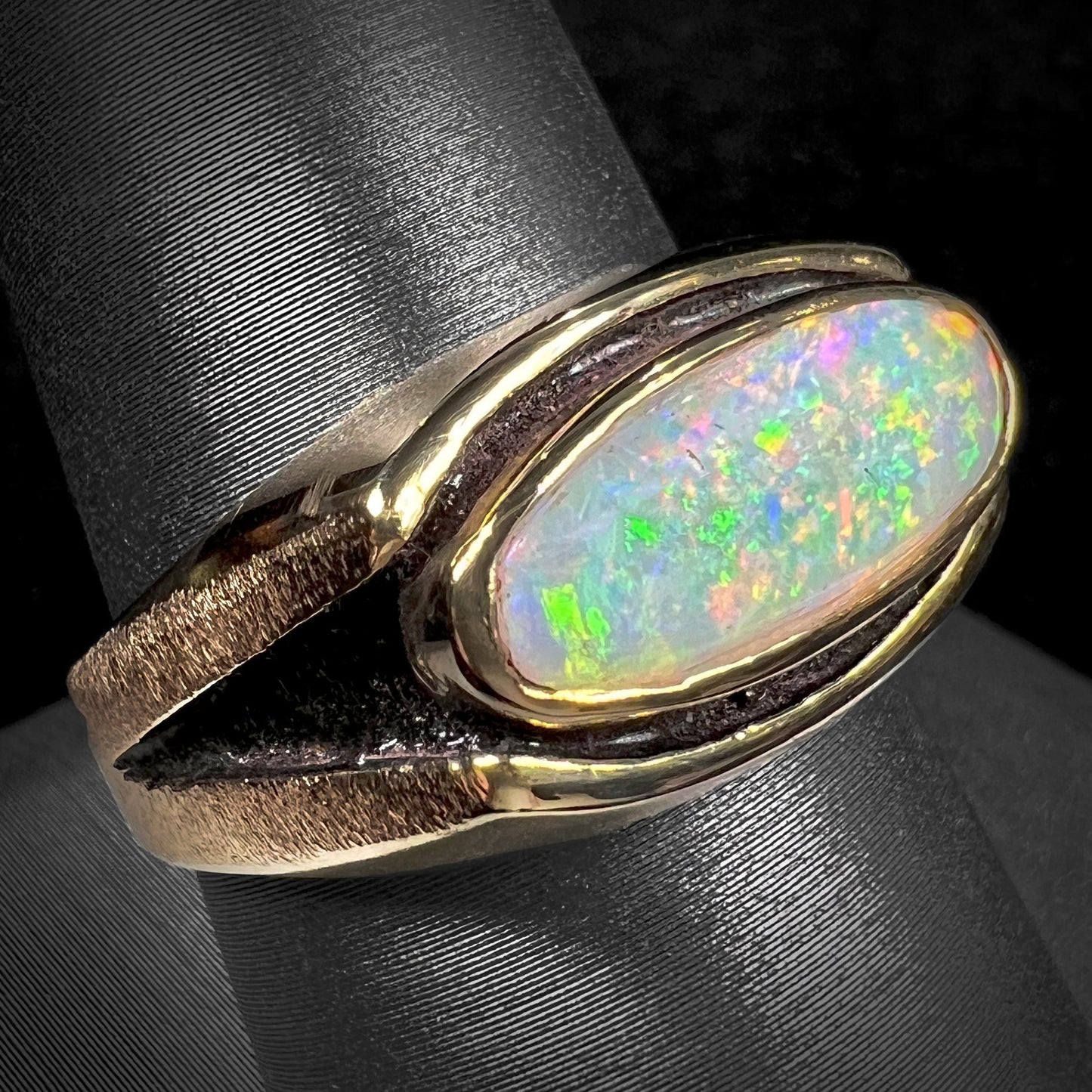 An Australian white crystal opal men's ring in solid yellow gold. The recesses of the ring have been blackened.