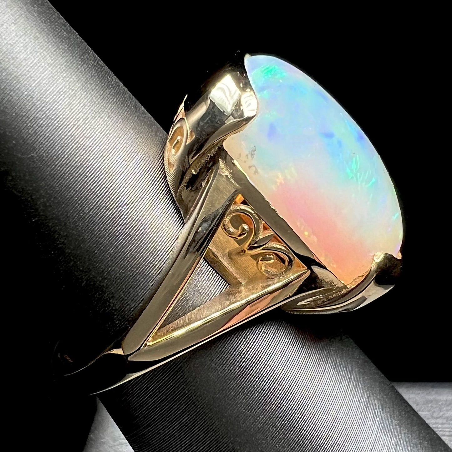 A ladies' yellow gold split shank ring half-bezel set with a barrel cabochon cut natural Ethiopian fire opal stone.
