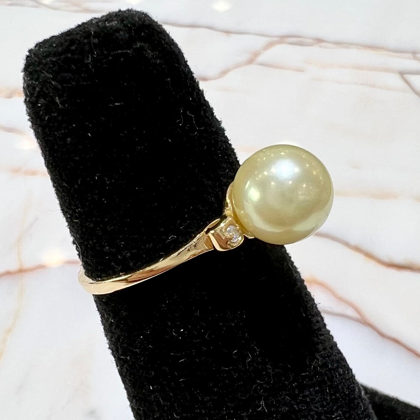 A simple, vintage, yellow gold pearl ring set with two side diamonds.