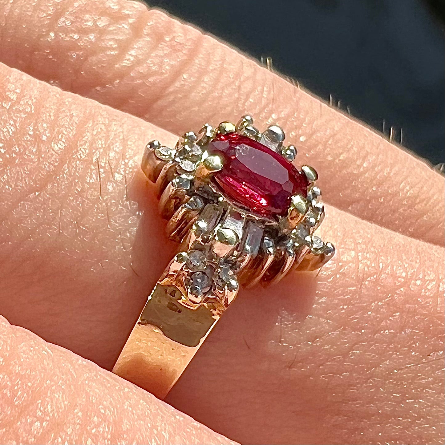 A yellow gold ring set with an oval cut red spinel and diamond rounds and baguettes.