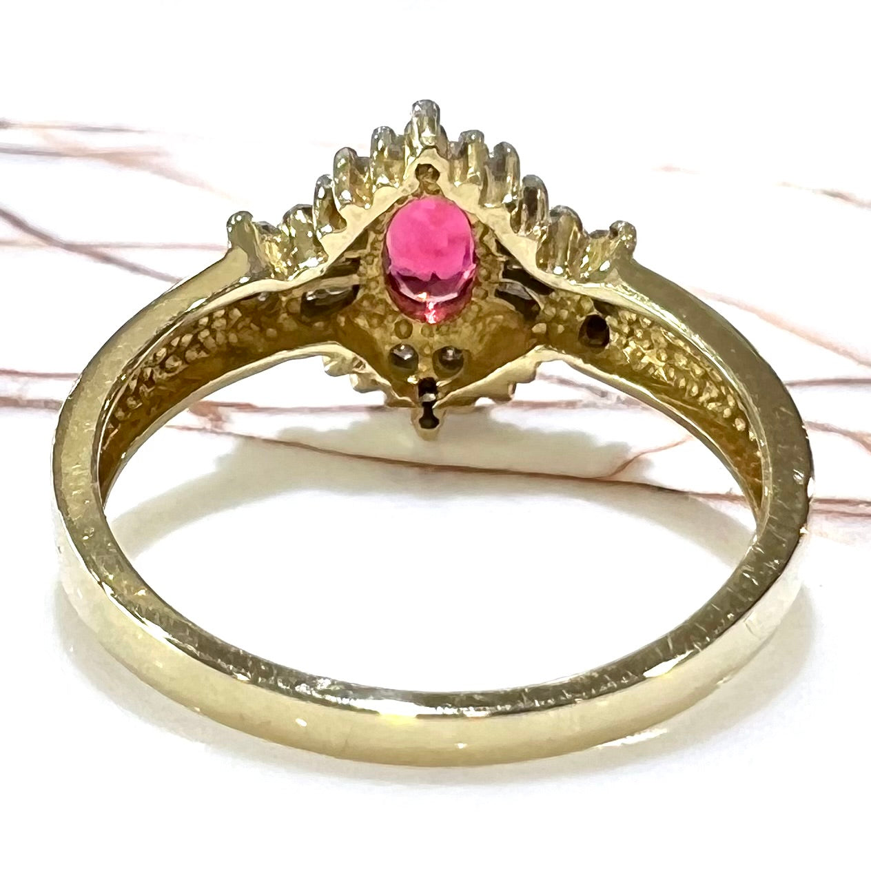 A yellow gold ring set with an oval cut red spinel and diamond rounds and baguettes.