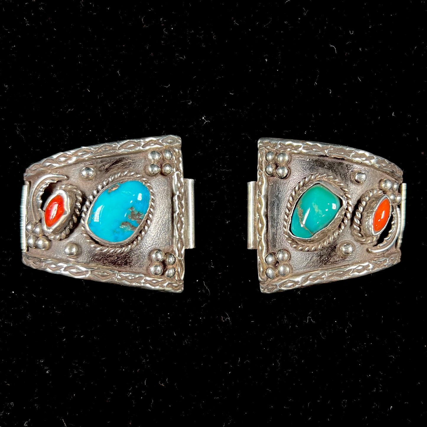 A pair of Navajo made sterling silver watch cuffs set with turquoise and coral stones.
