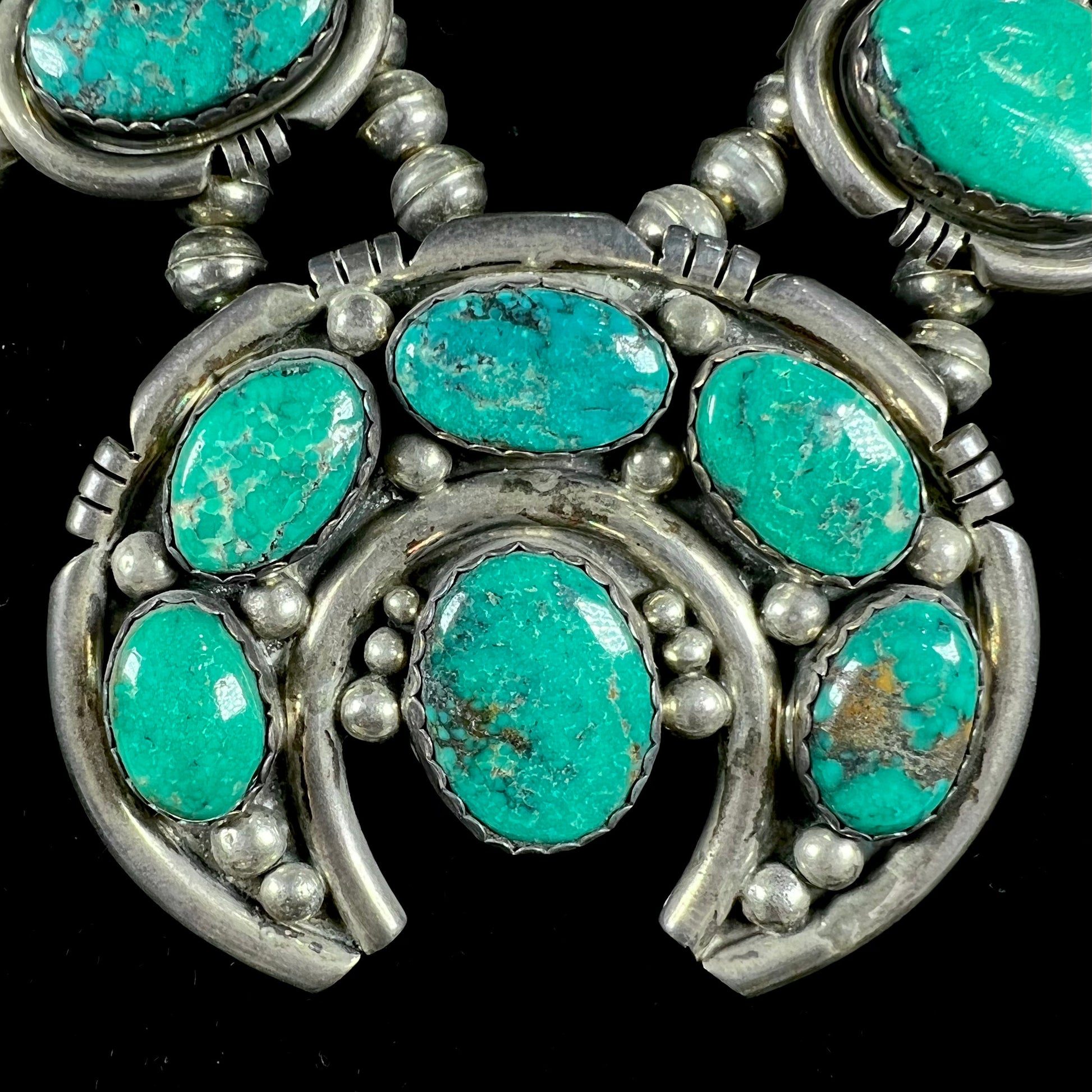 A silver Kingman turquoise squash blossom necklace.  The necklace is made with handmade Navajo pearls.