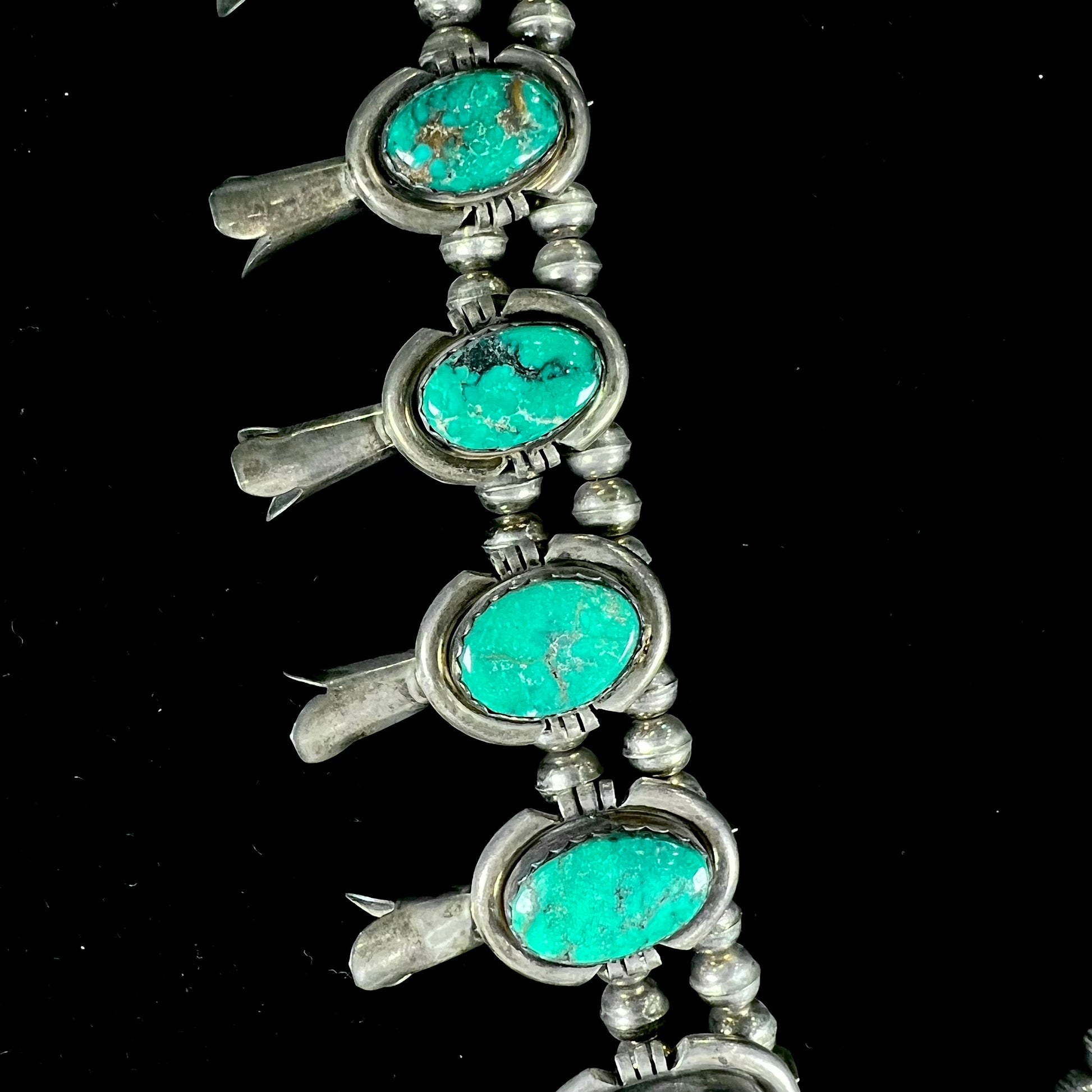 A silver Kingman turquoise squash blossom necklace.  The necklace is made with handmade Navajo pearls.