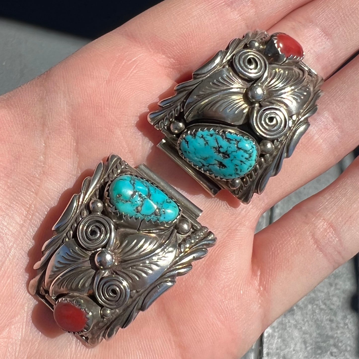 A pair of sterling silver watch cuffs set with turquoise and coral stones.