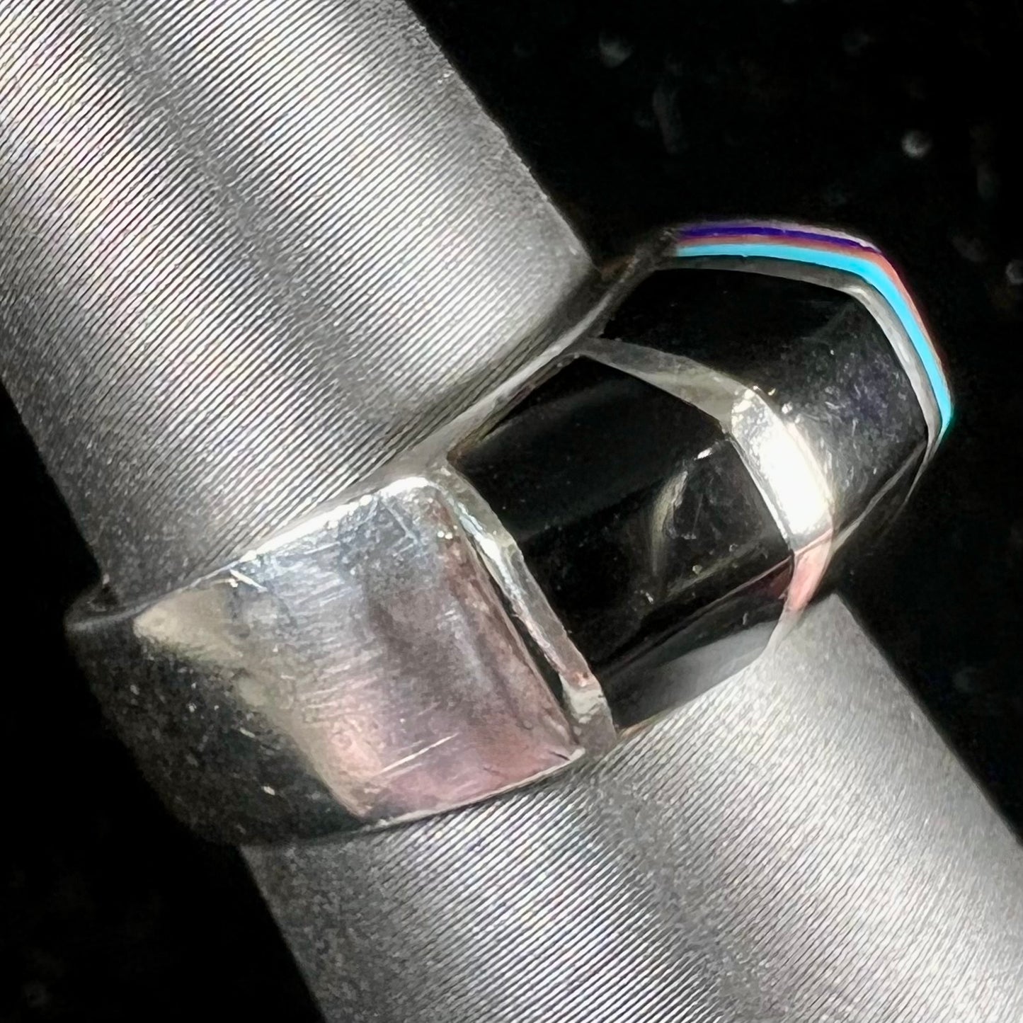 A sterling silver ring inlaid with onyx, turquoise, coral, lapis lazuli, and mother of pearl stones.