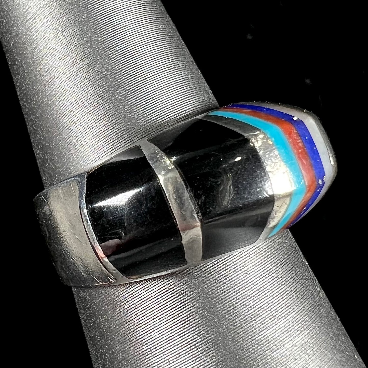 A sterling silver ring inlaid with onyx, turquoise, coral, lapis lazuli, and mother of pearl stones.