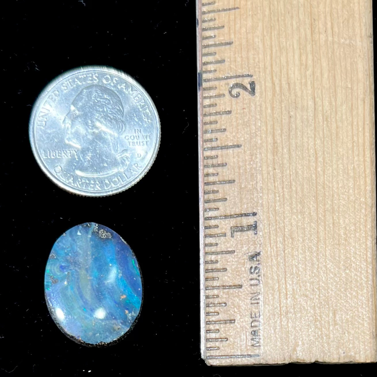A loose, oval cabochon cut boulder opal stone from Queensland, Australia. The stone is predominantly blue.