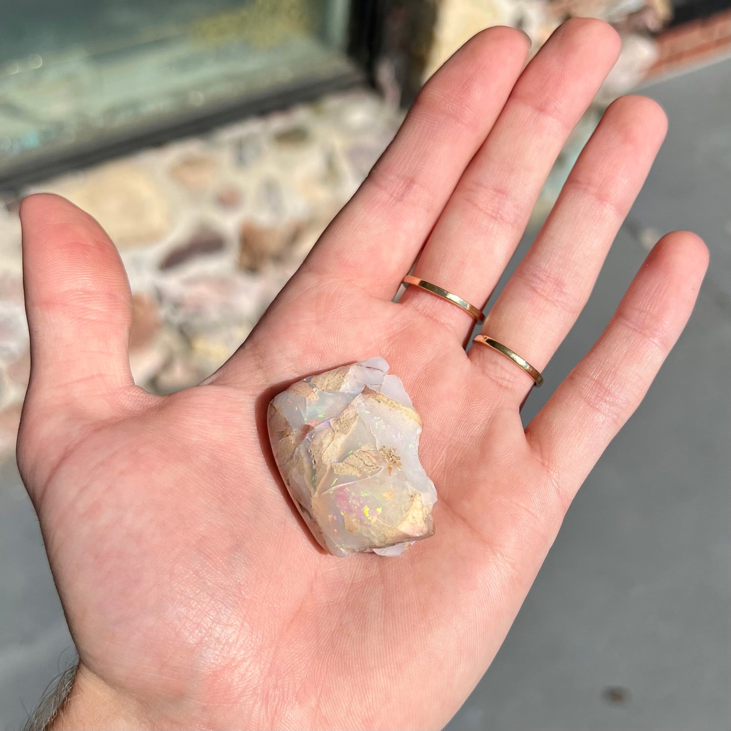 A preform polished matrix opal specimen from White Bluffs, Australia. Predominant colors are red, green, and violet.