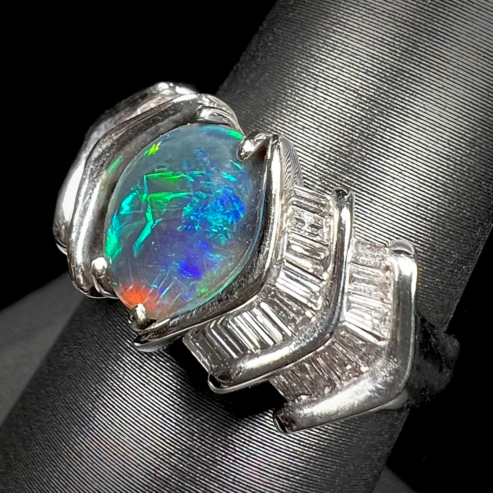 A white gold ring set with a Lightning Ridge natural black opal and baguette cut diamonds.