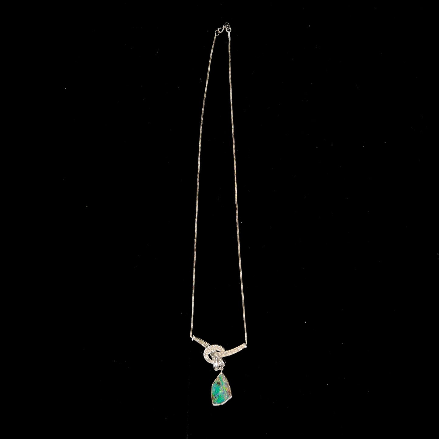 A white gold necklace set with diamonds and a dangling, bezel set boulder opal.