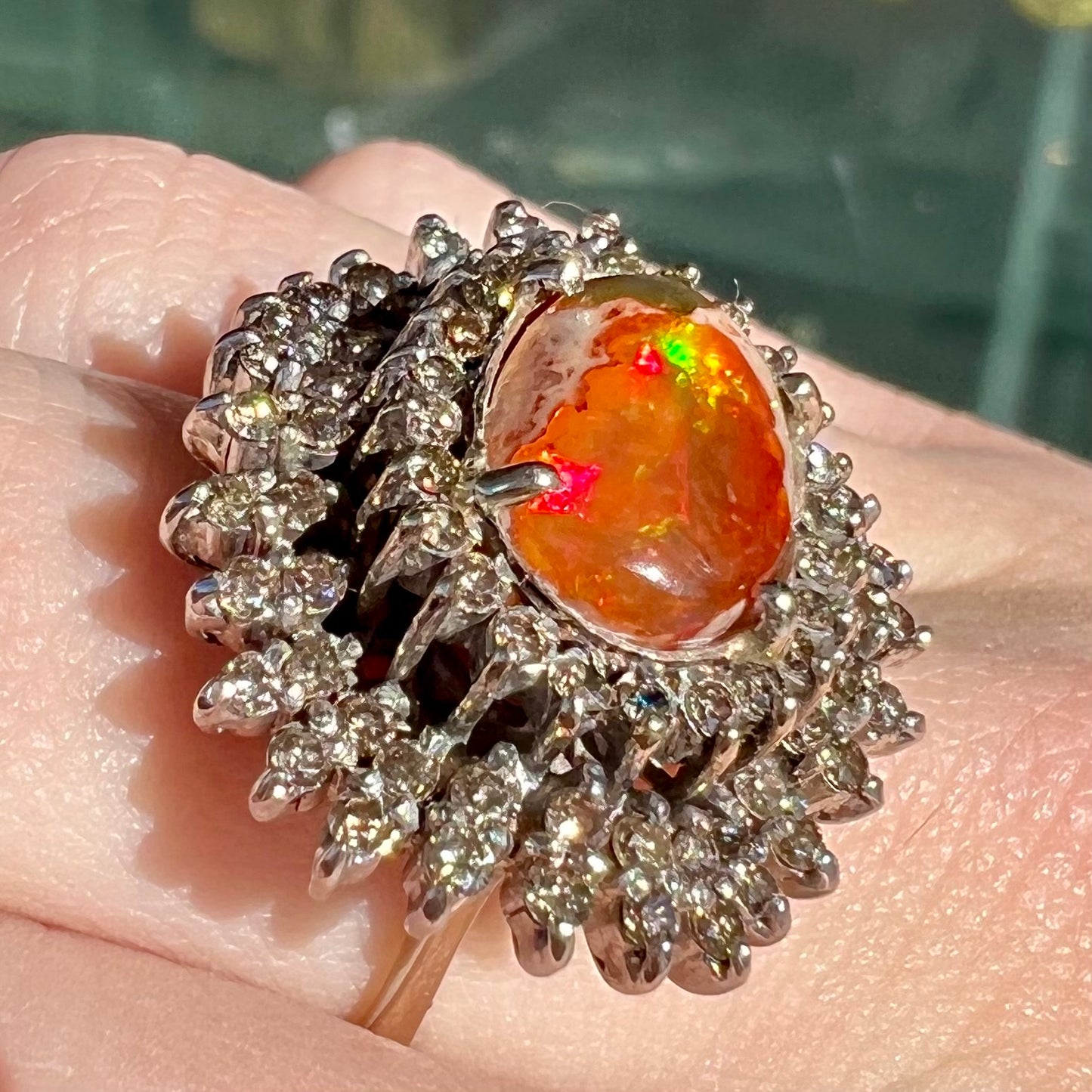 An 18k white gold orange fire opal ring set with a triple halo of diamonds.