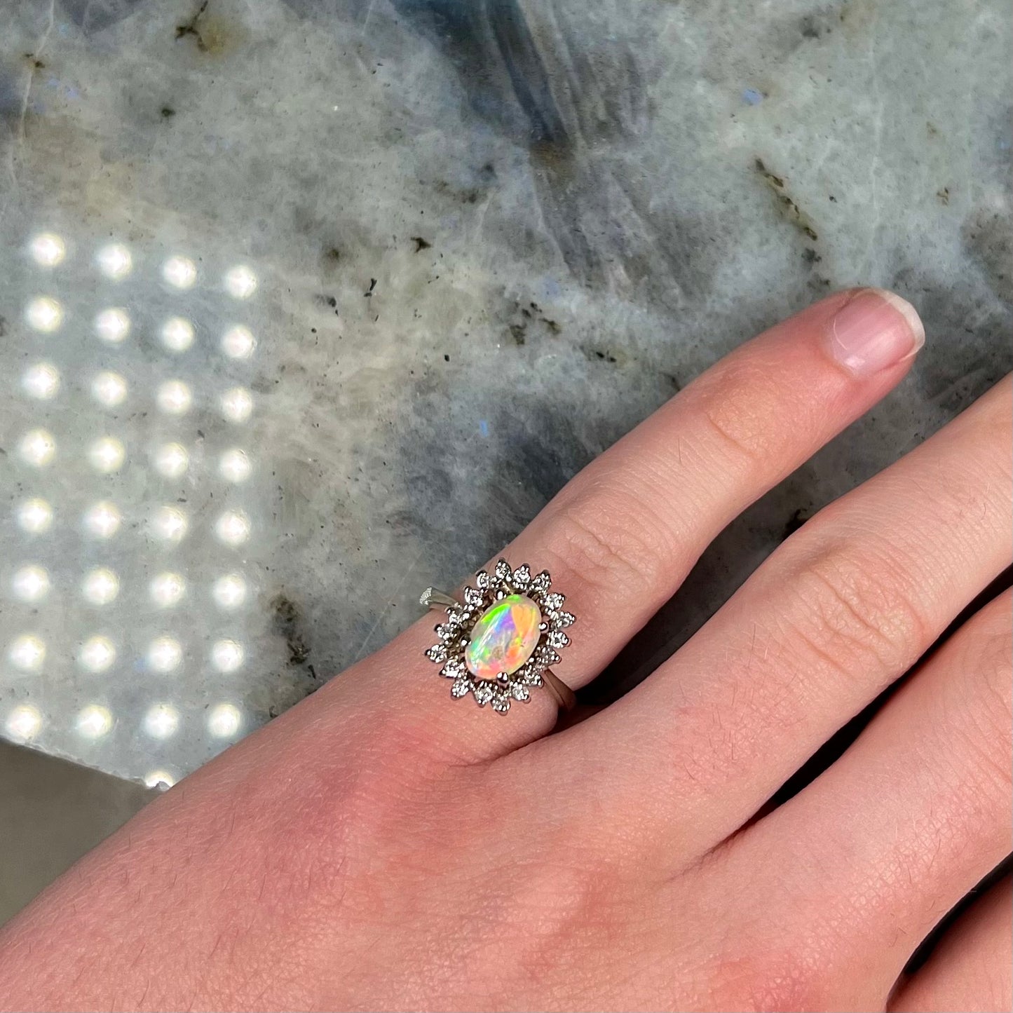A white crystal opal ring cast in white gold with a halo of round cut diamonds.