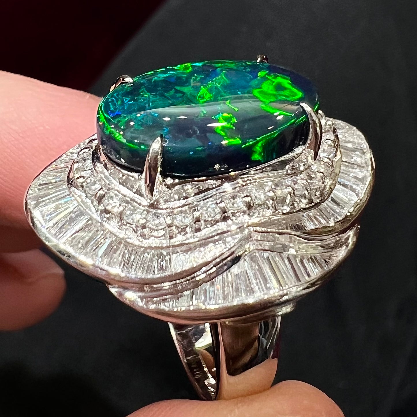 A ladies' platinum diamond halo ring set with a natural black opal stone from Lightning Ridge, Australia.