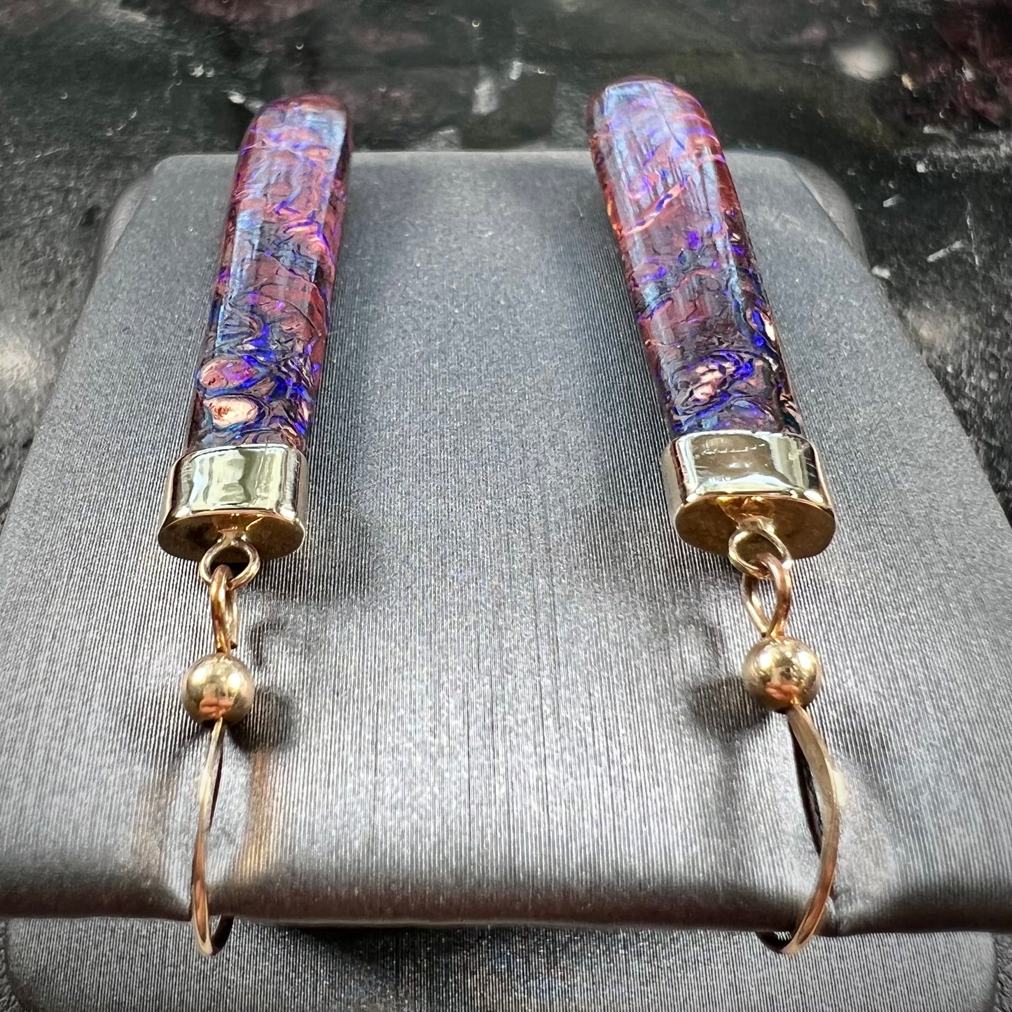 A pair of yellow gold cap Koroit boulder opal dangle earrings. Purple highlights are seen.