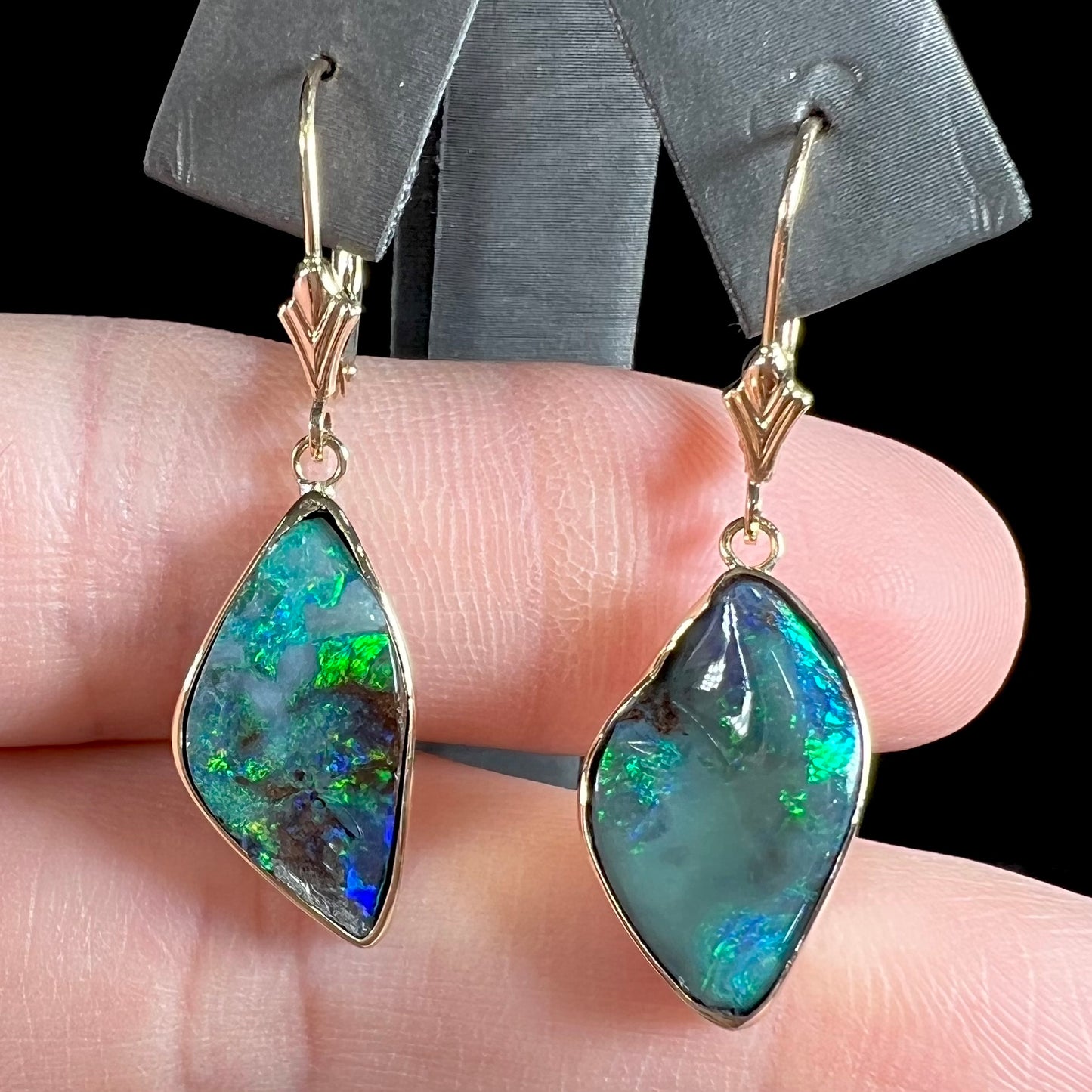 A pair of yellow gold dangle earrings set with Australian boulder opal stones.