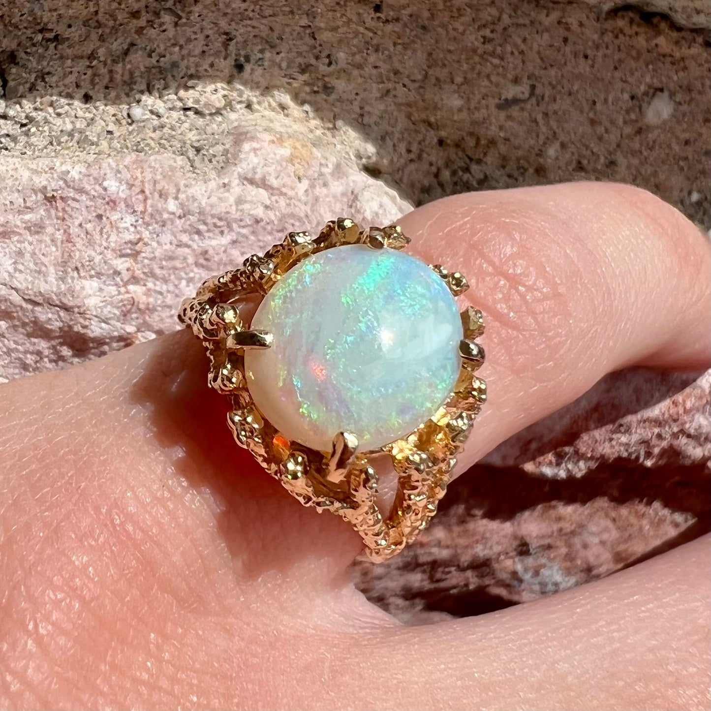 A yellow gold solitaire engagement ring set with an oval cabochon cut white crystal opal.