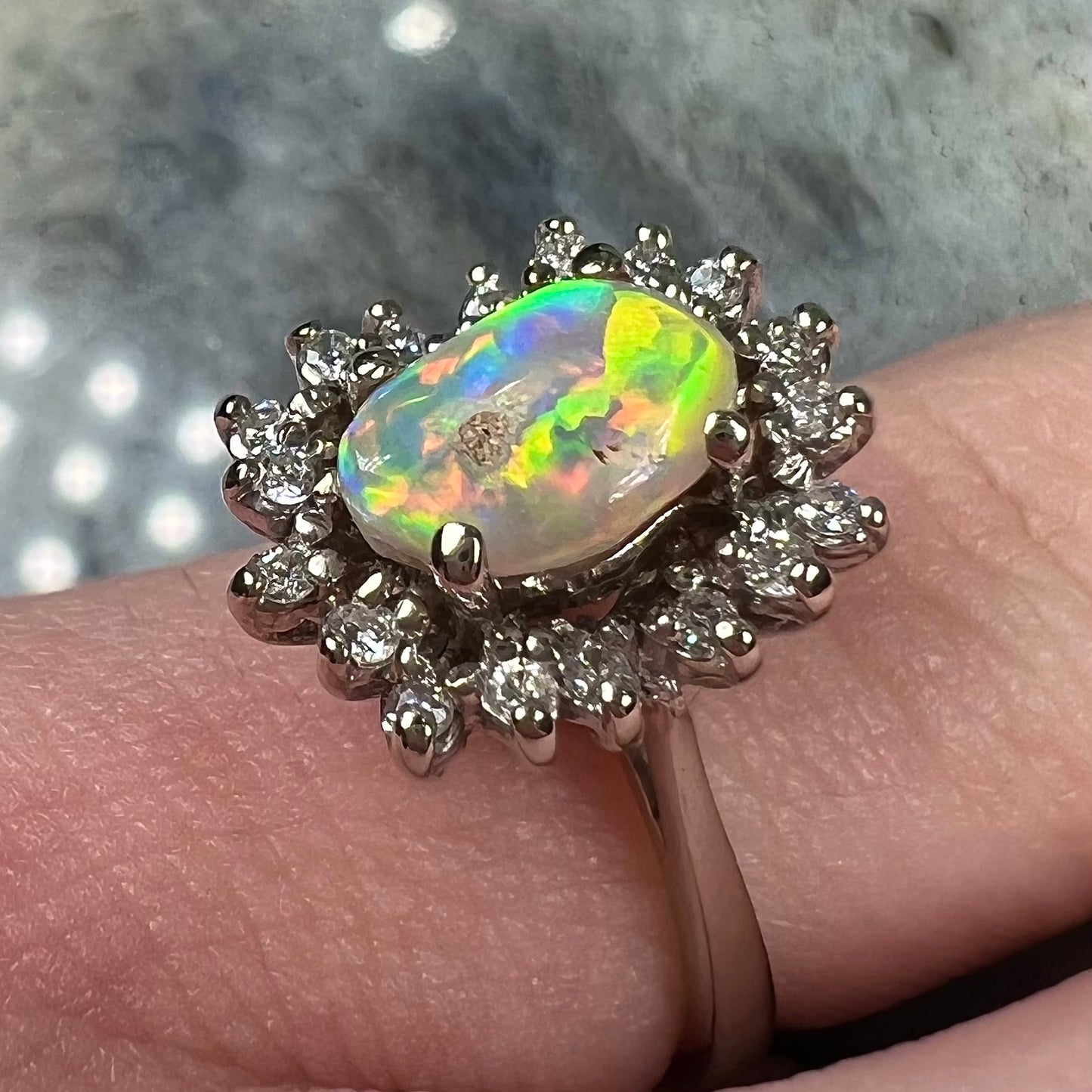 A white crystal opal ring cast in white gold with a halo of round cut diamonds.