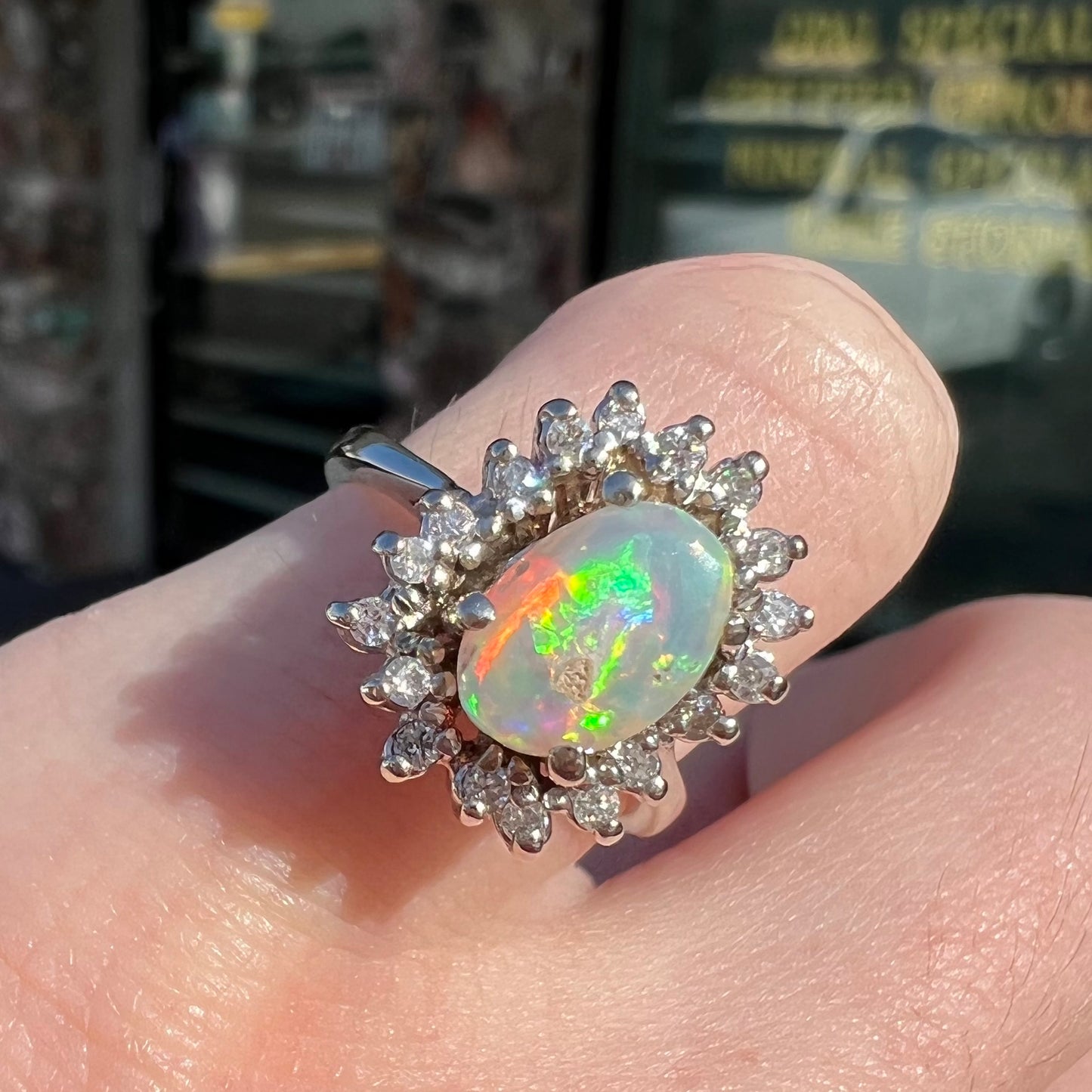 A white crystal opal ring cast in white gold with a halo of round cut diamonds.