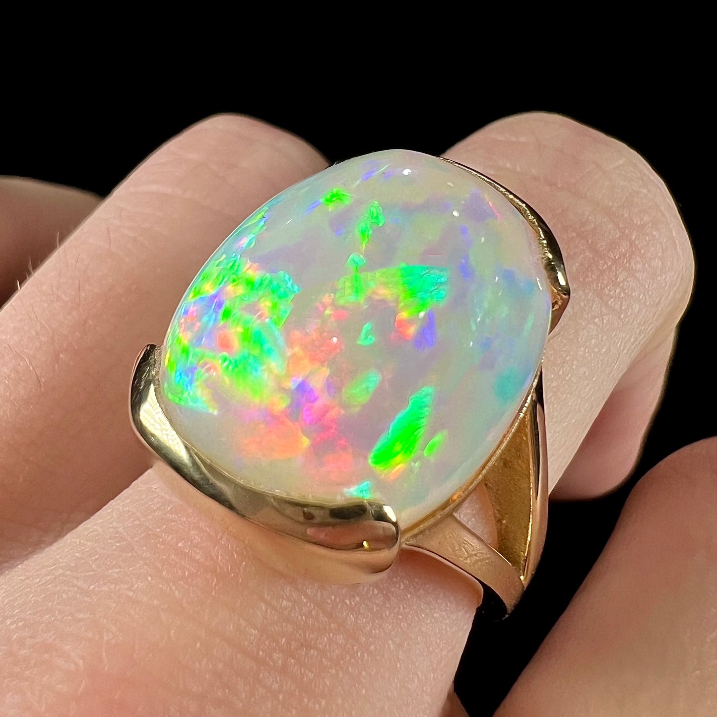 A ladies' yellow gold split shank ring half-bezel set with a barrel cabochon cut natural Ethiopian fire opal stone.