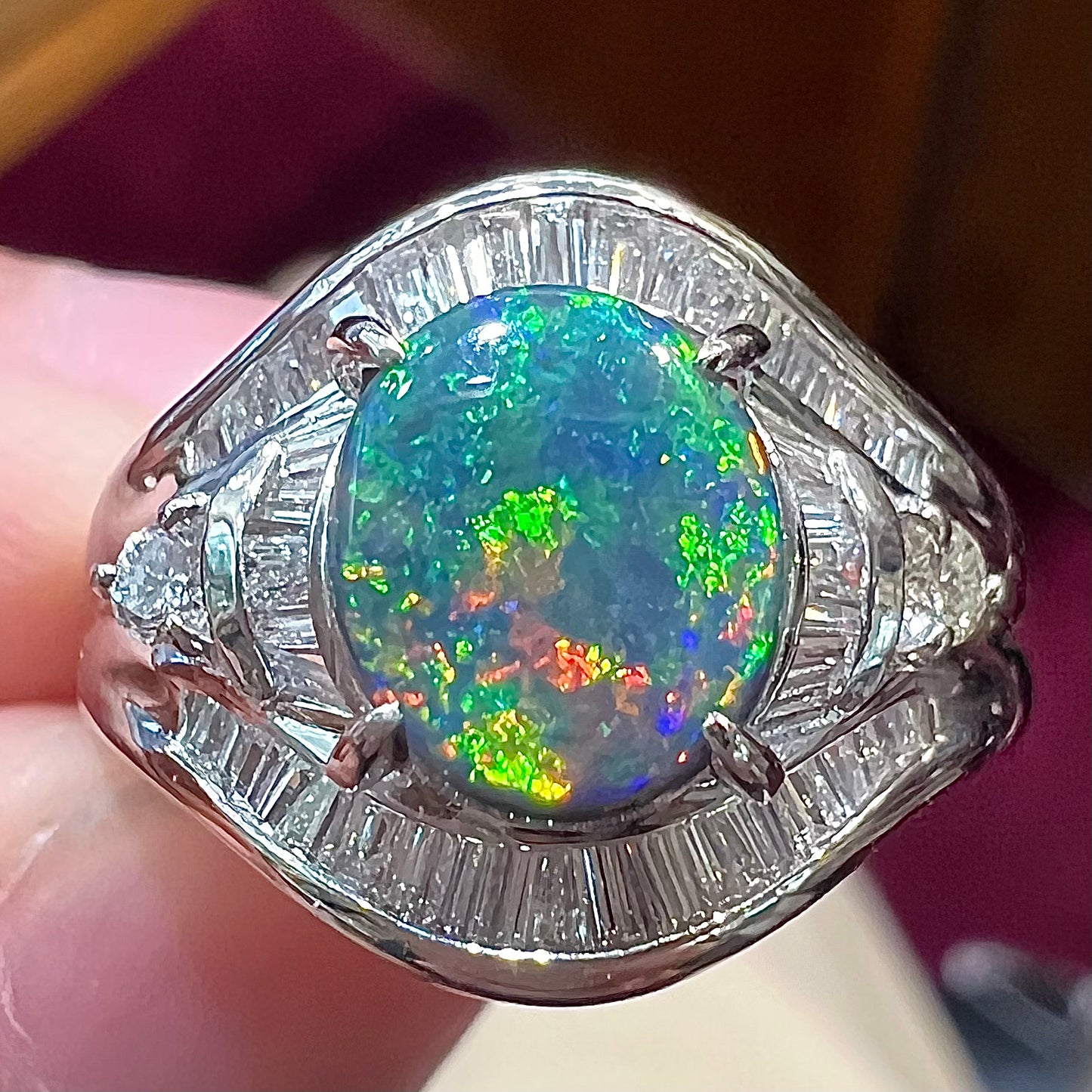 A platinum Lightning Ridge black opal ring set with baguette cut diamonds. The opal is an oval cabochon cut.
