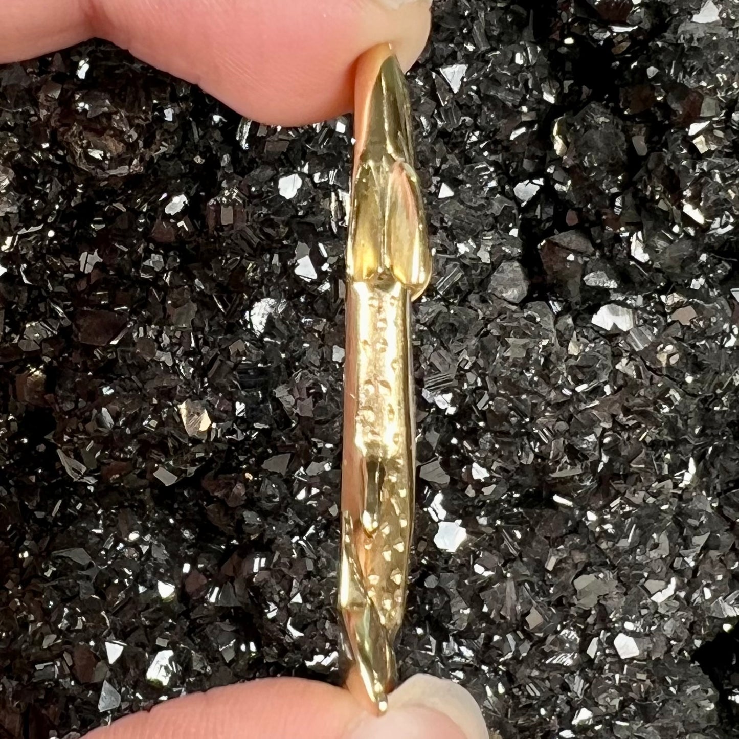 A yellow gold fish pendant detailed to look like a rainbow trout. The body of the fish is set with a color changing black opal stone.