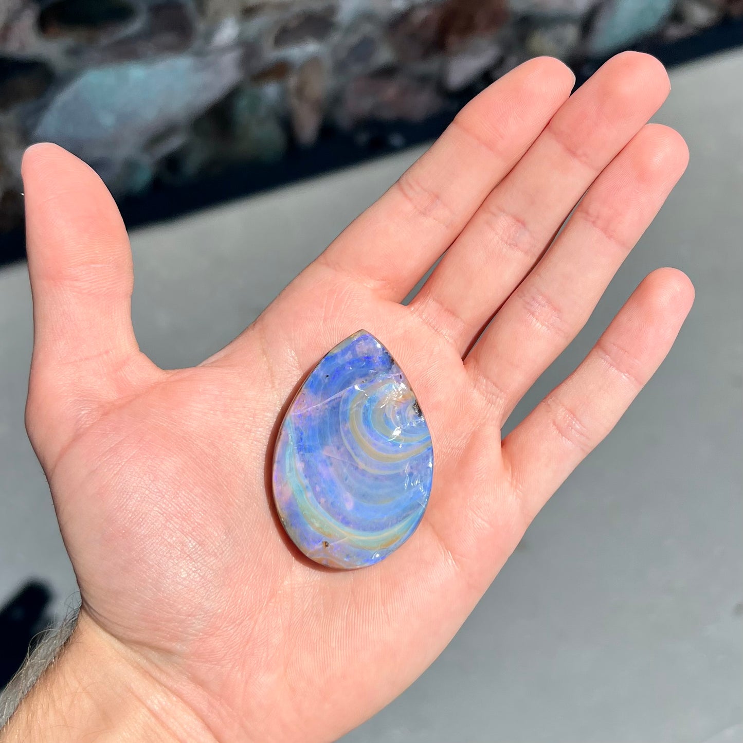 A loose, polished Quilpie boulder opal stone from Queensland, Australia. The opal displays a blue flow pattern.