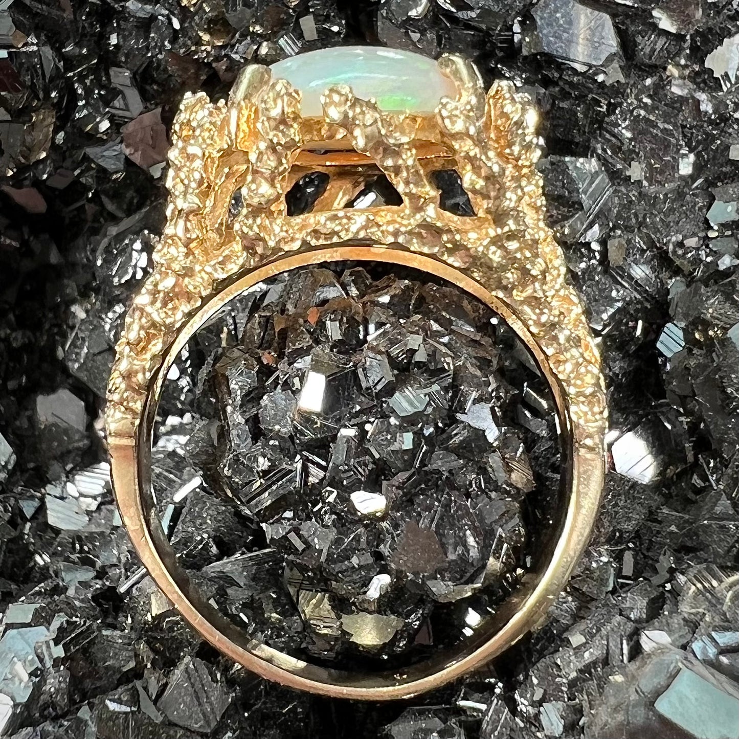 A yellow gold solitaire engagement ring set with an oval cabochon cut white crystal opal.