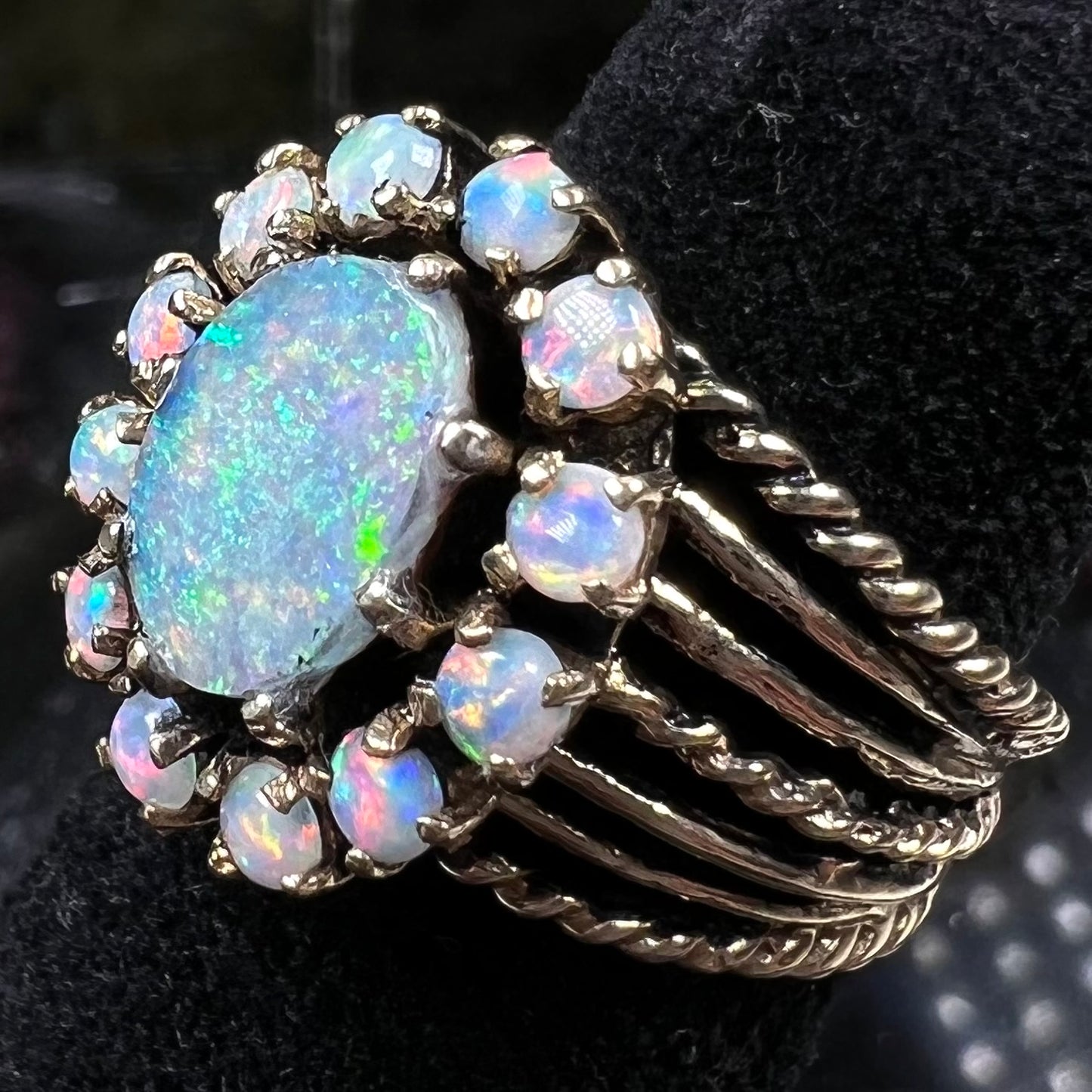 Vintage yellow gold oval opal cabochon ring set with 12 round opals in a halo around the center stone.