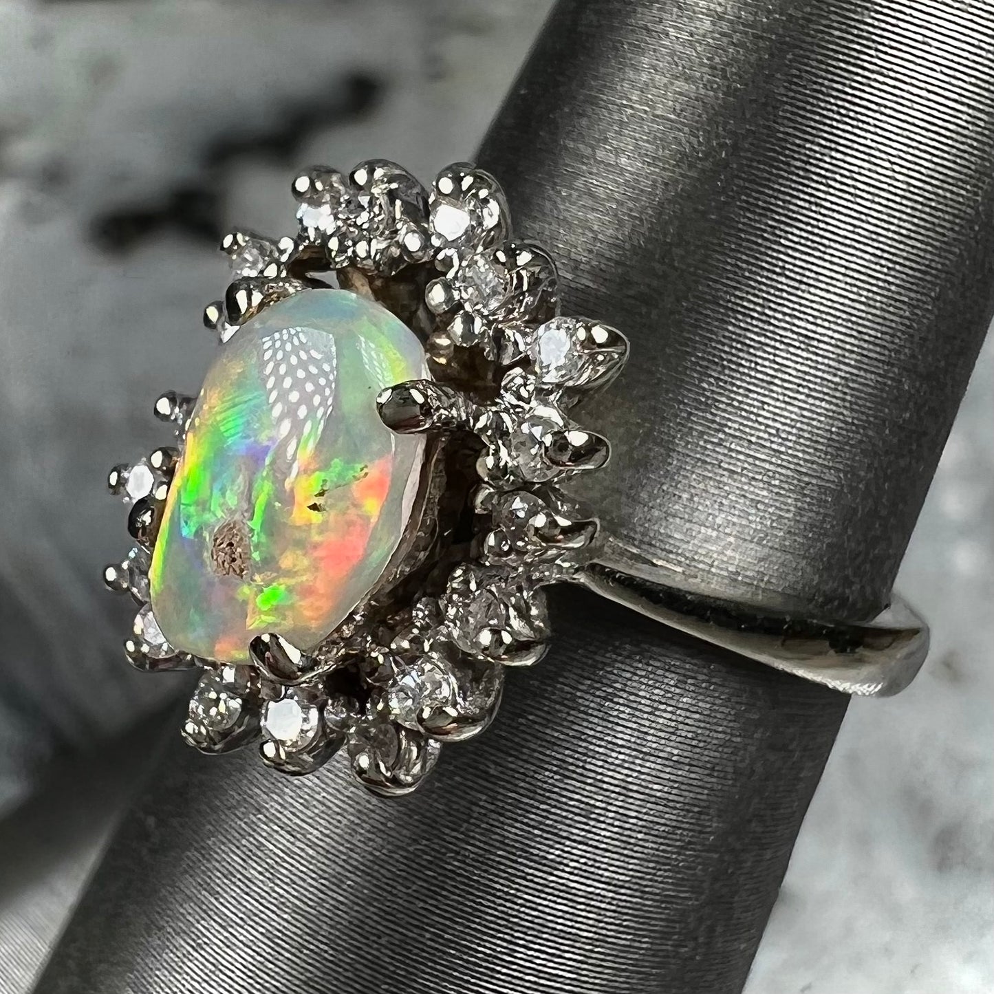 A white crystal opal ring cast in white gold with a halo of round cut diamonds.