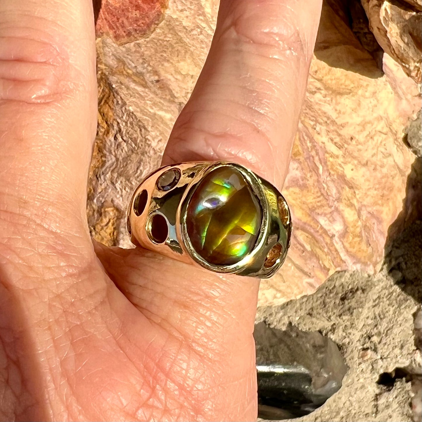 Men's rainbow fire agate ring set in yellow gold with champagne diamonds. The ring style has holes.