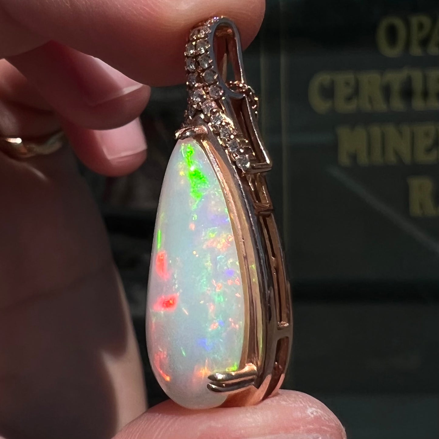 A rose gold, teardrop shaped fire opal and diamond necklace on a cable chain.