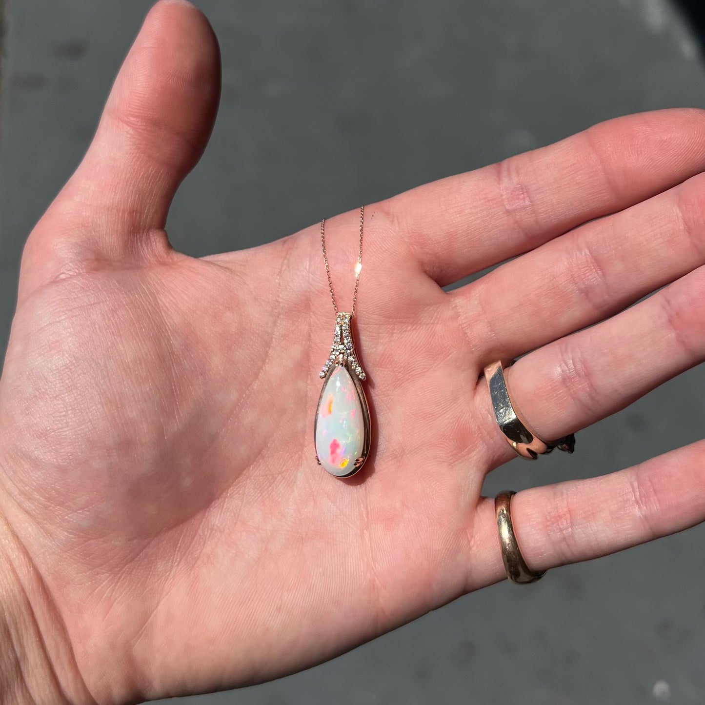 A rose gold, teardrop shaped fire opal and diamond necklace on a cable chain.