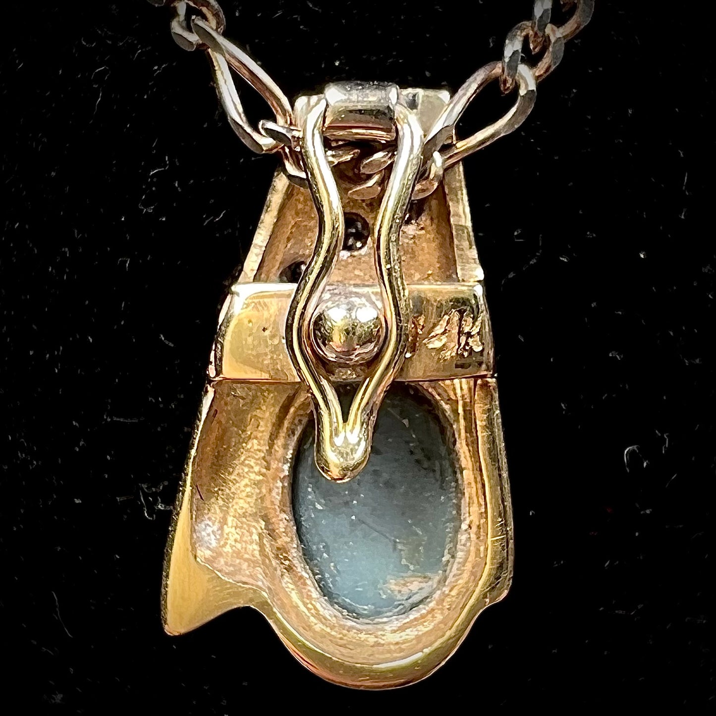 A yellow gold natural, Australian black opal necklace set with three round diamond accents.